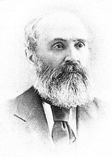 Black and white image of bald middle aged man with white beard, facial profile and upper body.