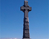Celtic Cross with person approaching, blue sky and river in background.