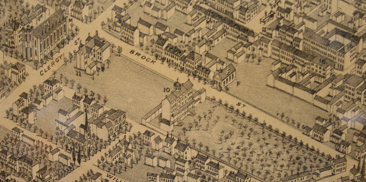 Black and white illustrated map, four city blocks in foreground including large church with steeple, large four storey building with sloped roof and cupola, surrounded field and orchard, outer streets more densely occupied with smaller houses.