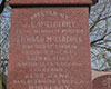 Monument de granite rouge, surmonté d’une croix et installé sur un socle de pierre de couleur grise. Le mot McElderry est inscrit sur la pierre. Un arbre et de l’herbe sont aperçus à l’arrière-plan.