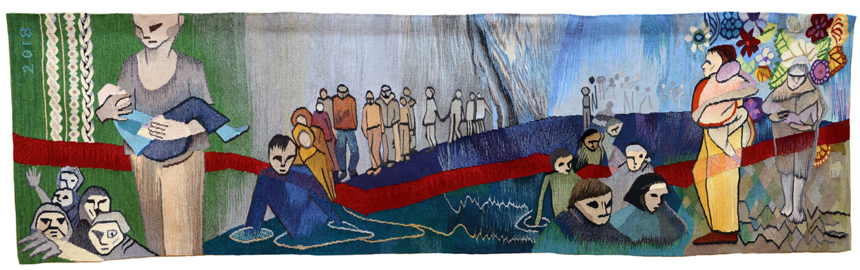 Long rectangular tapestry with many stylized cartoonish figures. From left, a person walking holding a child can be seen with huddled group of five people below, against green background and 2018 written top left. Middle section features man in blue reclining with large group of people walking single file behind him, against a blue and grey background with a large red stripe winding across. Another group of five huddled people are featured to the right. On the far right, a woman in a red top and yellow trousers clasps a child to her chest, walking beside another woman in a veil also holding a child, with fruits and flowers above them and jagged stones below.